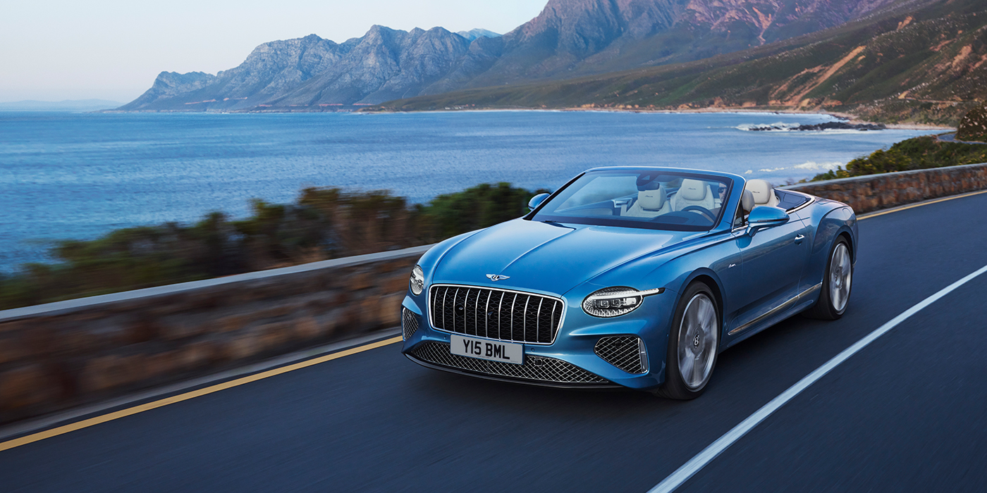 Bentley Gold Coast (Australia) New Bentley Continental GTC Azure convertible in Light Windsor blue paint with 22 inch Azure wheels and chrome grill, driving dynamically by the sea