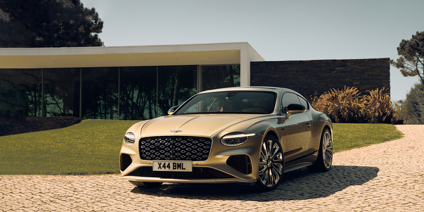 Bentley Gold Coast (Australia) Bentley Continental GT Mulliner coupe front three quarters in Patina paint parked outside a glass fronted building with a grass lawn behind it