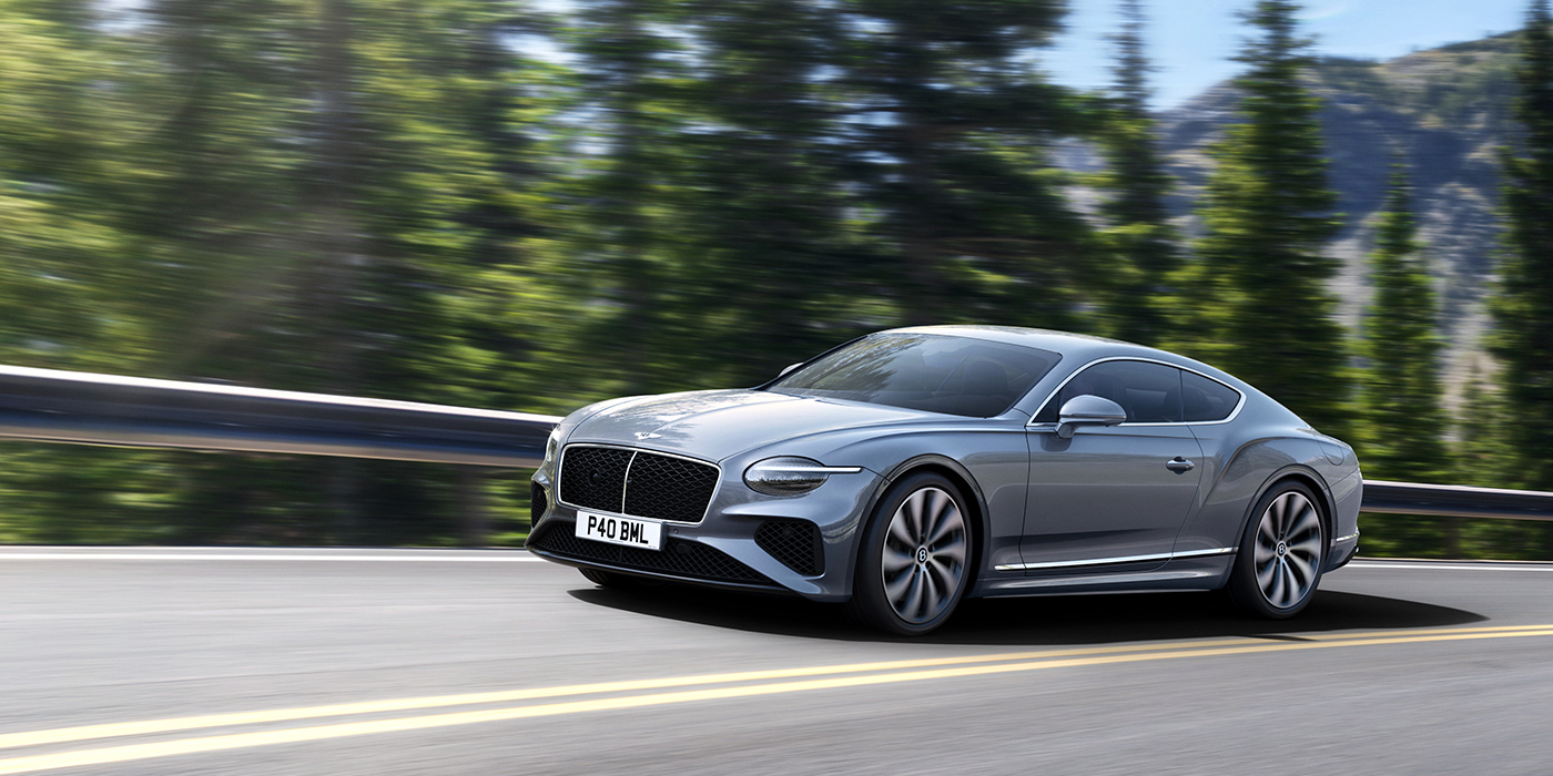 Bentley Gold Coast (Australia) New Bentley Continental GT coupe in Silverlake paint and 22 inch ten-spoke wheels, driving dynamically on a tree-lined road in the sunshine