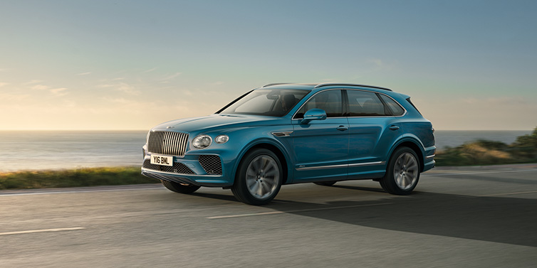 Bentley Gold Coast (Australia) Bentley Bentayga Azure SUV in Topaz blue paint driving dynamically by the ocean with 22 inch 10 spoke directional wheels