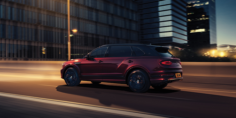 Bentley Gold Coast (Australia) Bentley Bentayga Extended Wheelbase Mulliner SUV in Cricket Ball red paint driving dynamically in city at night