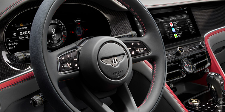 Bentley Gold Coast (Australia) Bentley Flying Spur Speed sedan front interior detail showing steering wheel and driver screens surrounded with Hotspur red and Gravity Grey hides